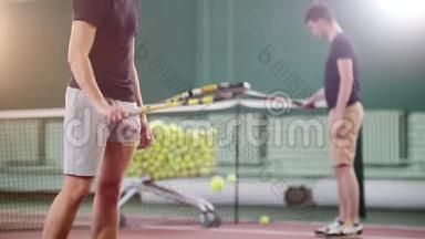 在网球场上训练。 两个年轻人从地板上击球